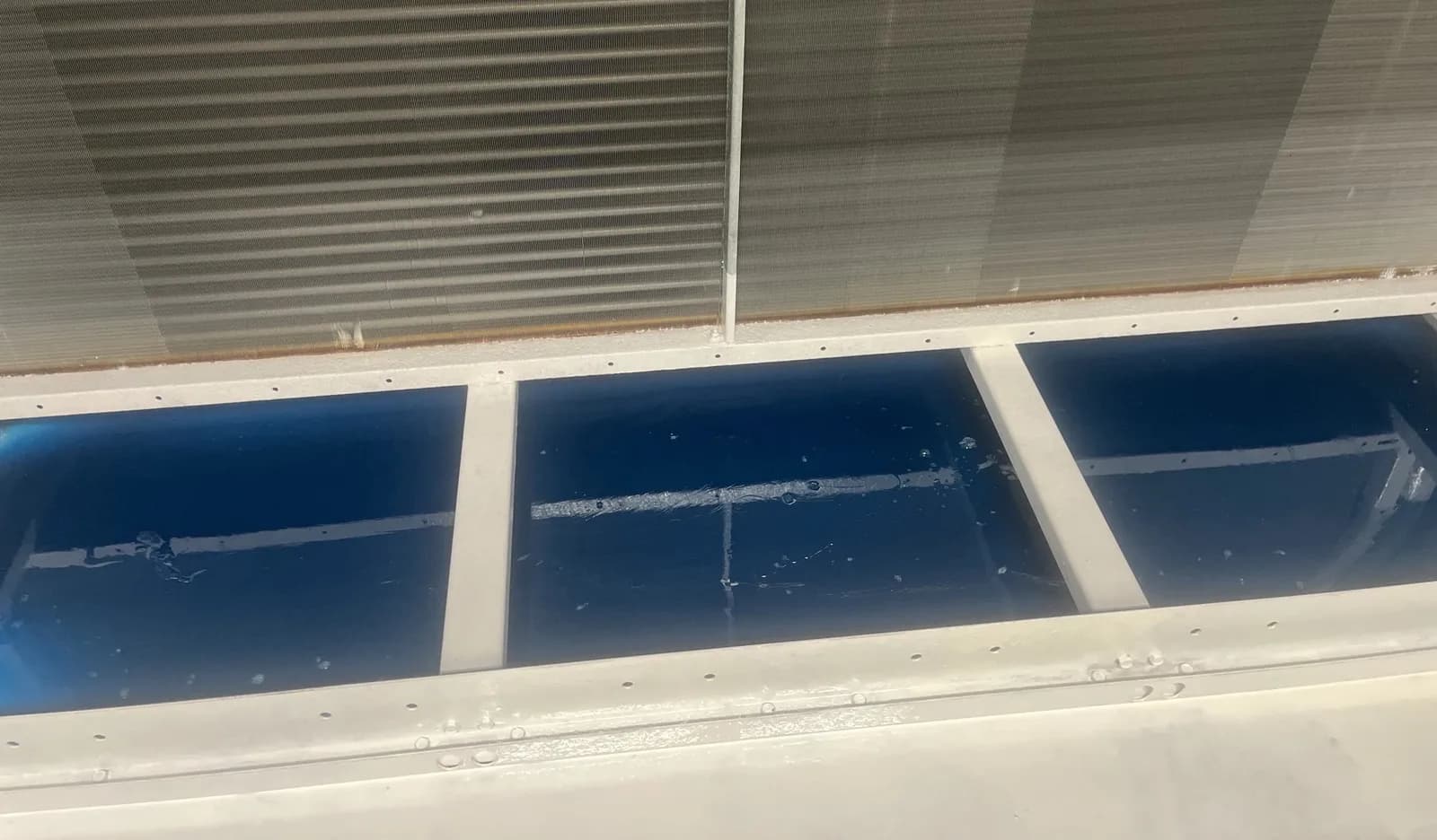 Restored condensate drain pans with protective coating applied, viewed along the coil face